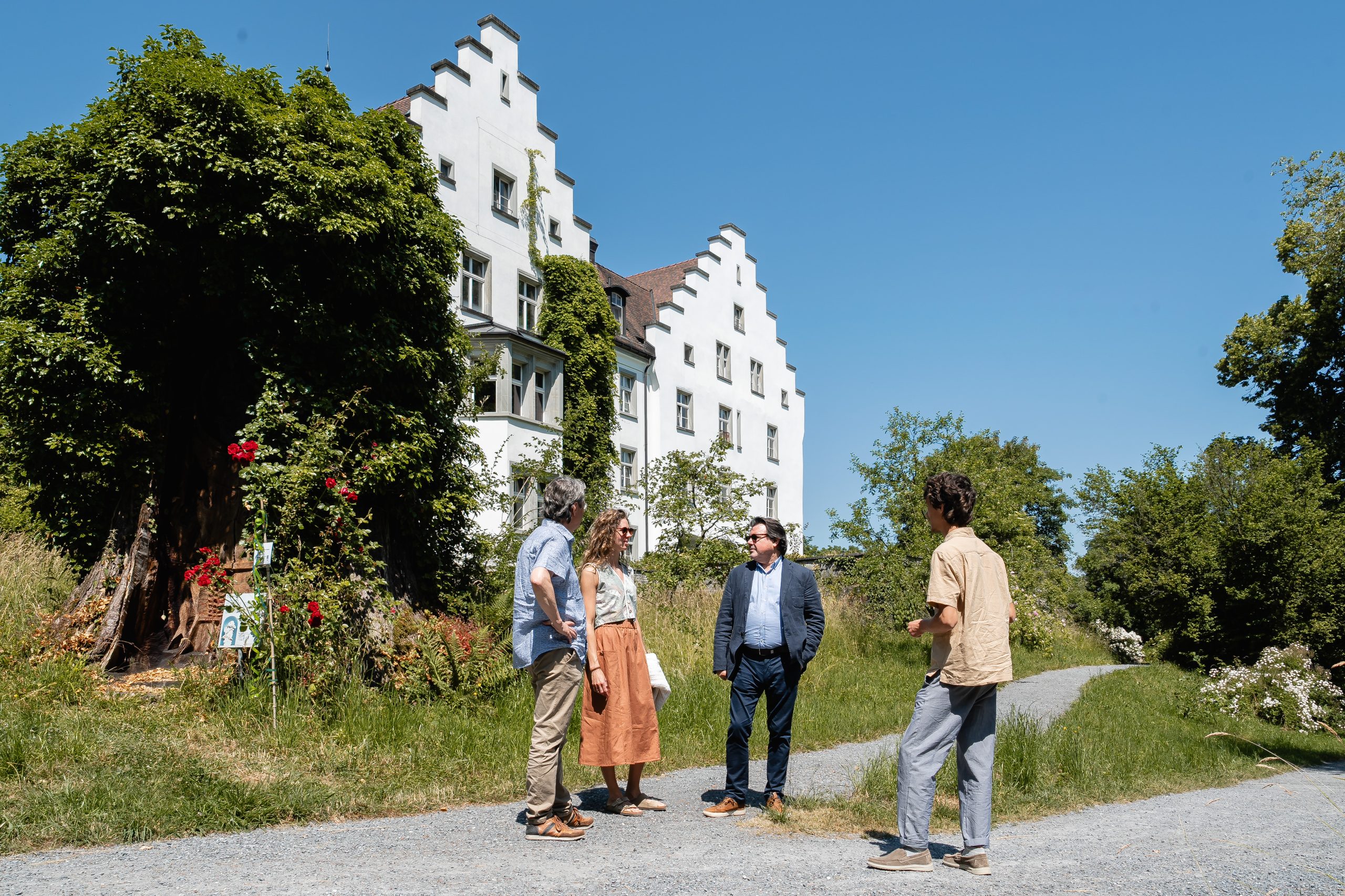 Vier Personen vor einem historischen Gebäude im Freien.